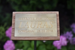 Misiņa plāksne ar gravētu tekstu uz statīva.