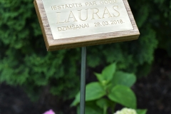 Misiņa plāksne ar gravētu tekstu uz statīva.
