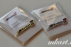 Misiņa un alumīnija  piespraude ar gravētu un krāsotu logo. Piespraudei magnēta stiprinājums.