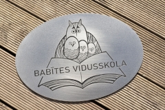 Gravēta nerūsējošā tērauda plāksne ar skolas logo.